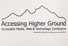 Logo bestehend aus Schriftzug: "Accessing Higher Ground. Accessible Media, Web & Technology Coference. Presented by AHEAD in Collaboration with ATHEN.". Darüber befindet sich eine Linie, die eine Berglandschaft formt.